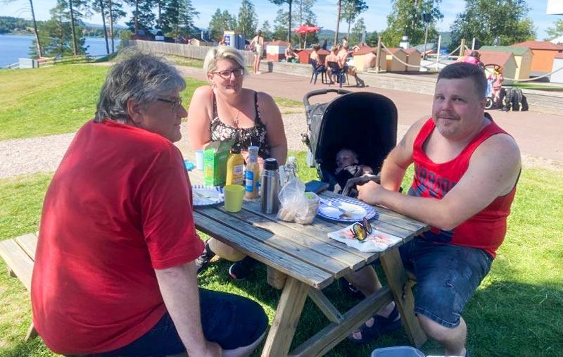 Bild på tre vuxna personer som fikar. 
