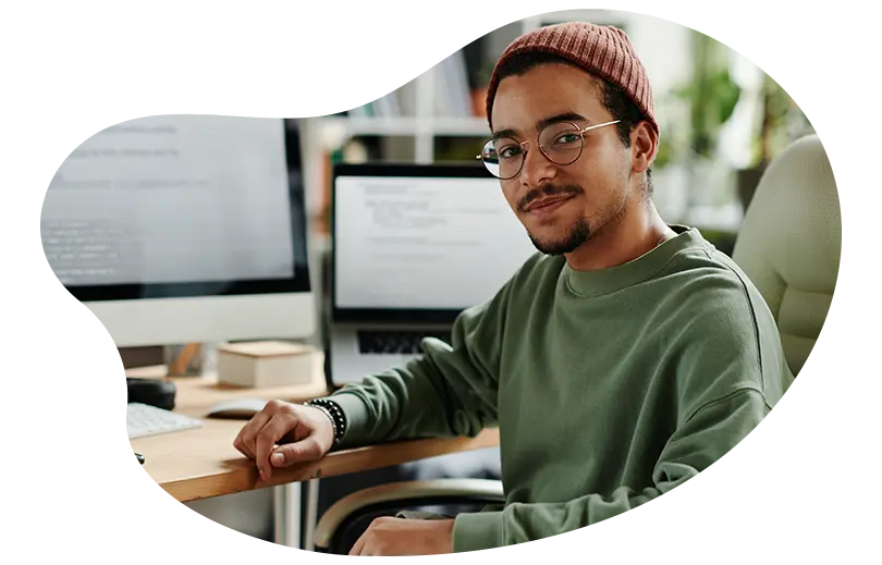 Ung man sitter vid datorbordet och tittar in i kameran